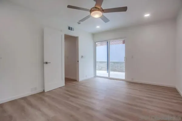 an empty room with wooden floor ceiling fan and windows