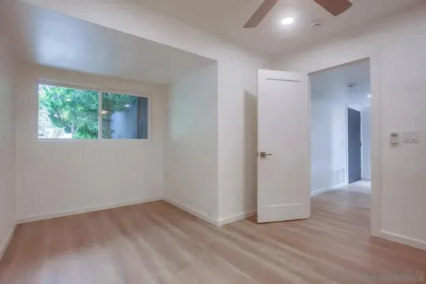 a view of an empty room with wooden floor and a window