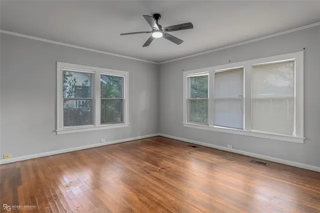 an empty room with wooden floor chandelier and windows