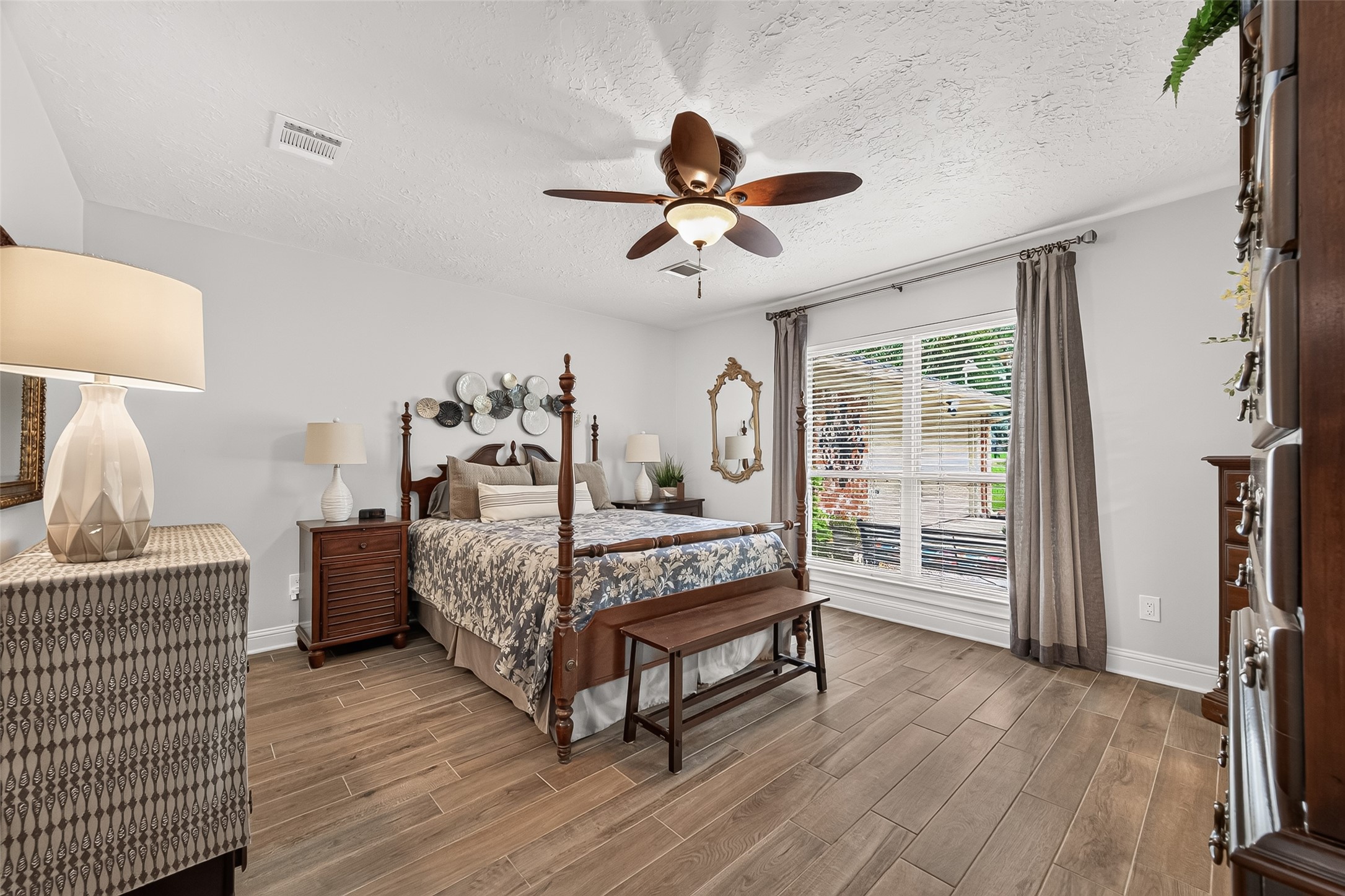 24719 Wilderness Road Spring, TX 77380 - Photo 25 of 42 This spacious primary bedroom features elegant ceramic tile flooring, a stylish ceiling fan, and ample natural light from large windows with blinds.