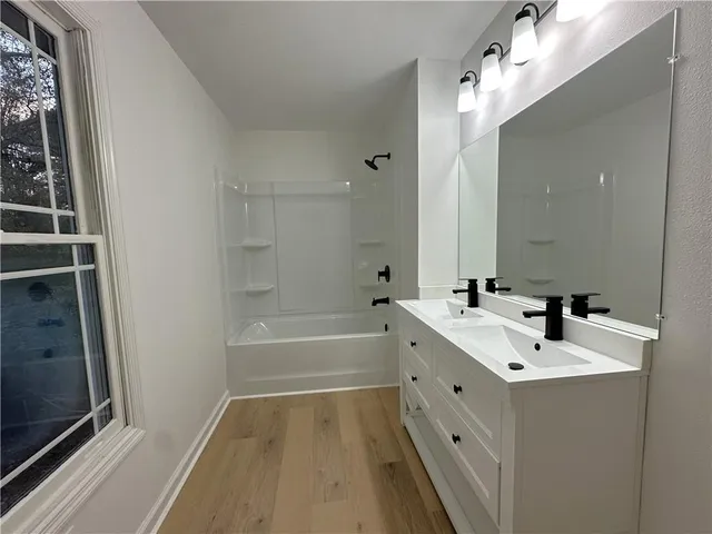 a bathroom with a double vanity sink a mirror and a bathtub