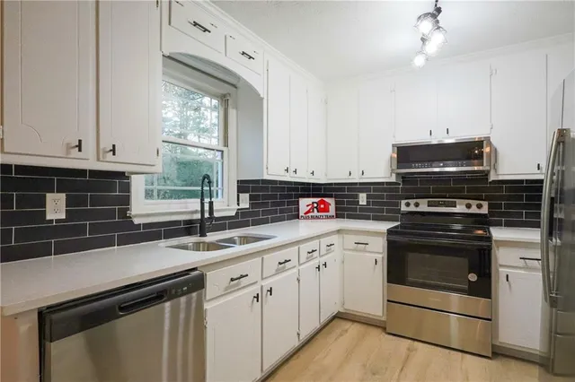 a kitchen with granite countertop a sink stainless steel appliances and cabinets