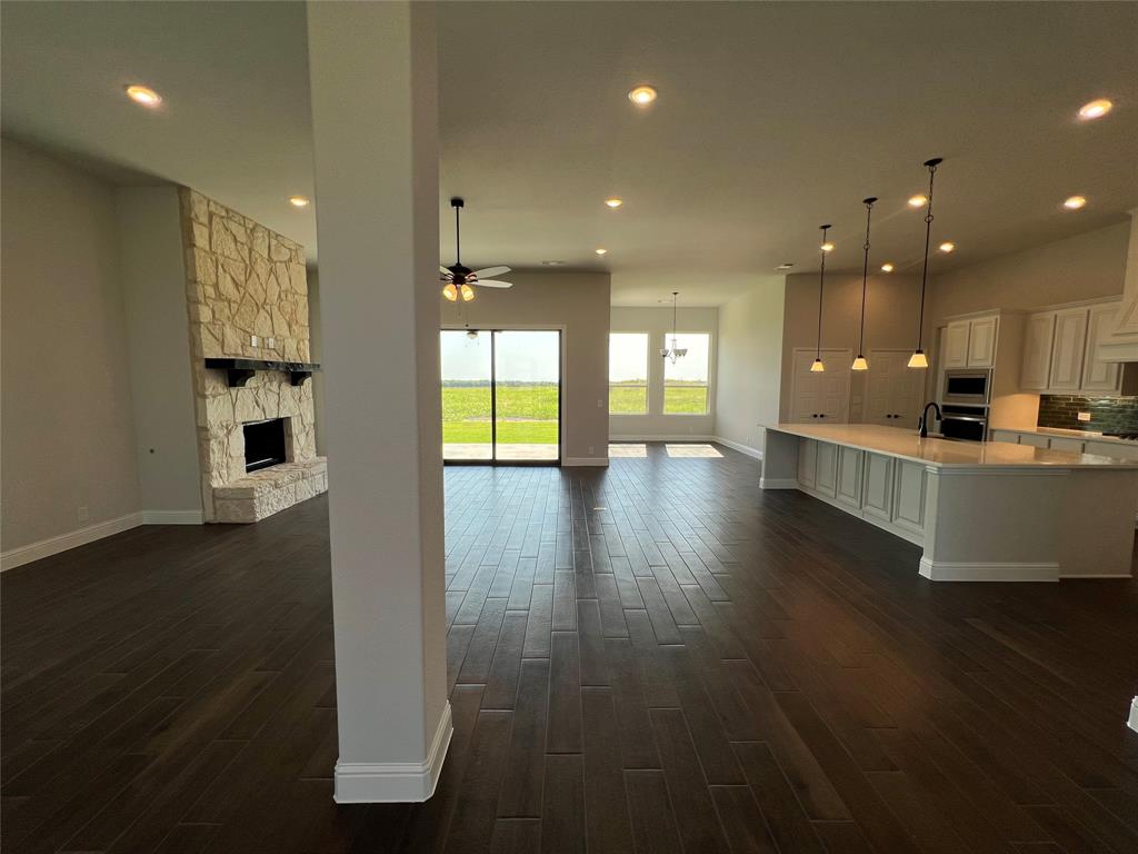 2108 Charters Circle Nevada, TX 75173 - Photo 7 of 37 Unfurnished living room featuring a stone fireplace, recessed lighting, dark wood-style floors, and a ceiling fan