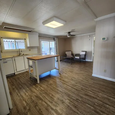 a view of a kitchen with kitchen island a sink wooden floor and a counter top space