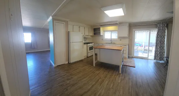 a room with kitchen island wooden floor and stainless steel appliances