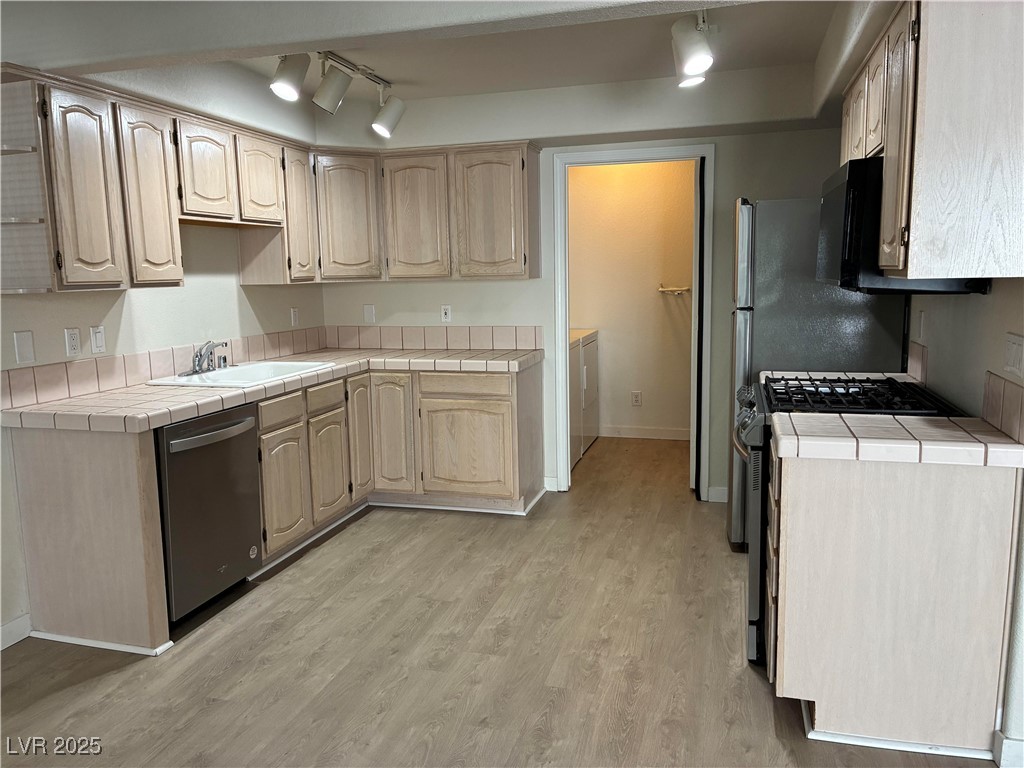 701 Capri Drive, Unit 5C Boulder City, NV 89005 - Photo 3 of 8 Kitchen with track lighting, tile countertops, light brown cabinetry, and appliances with stainless steel finishes