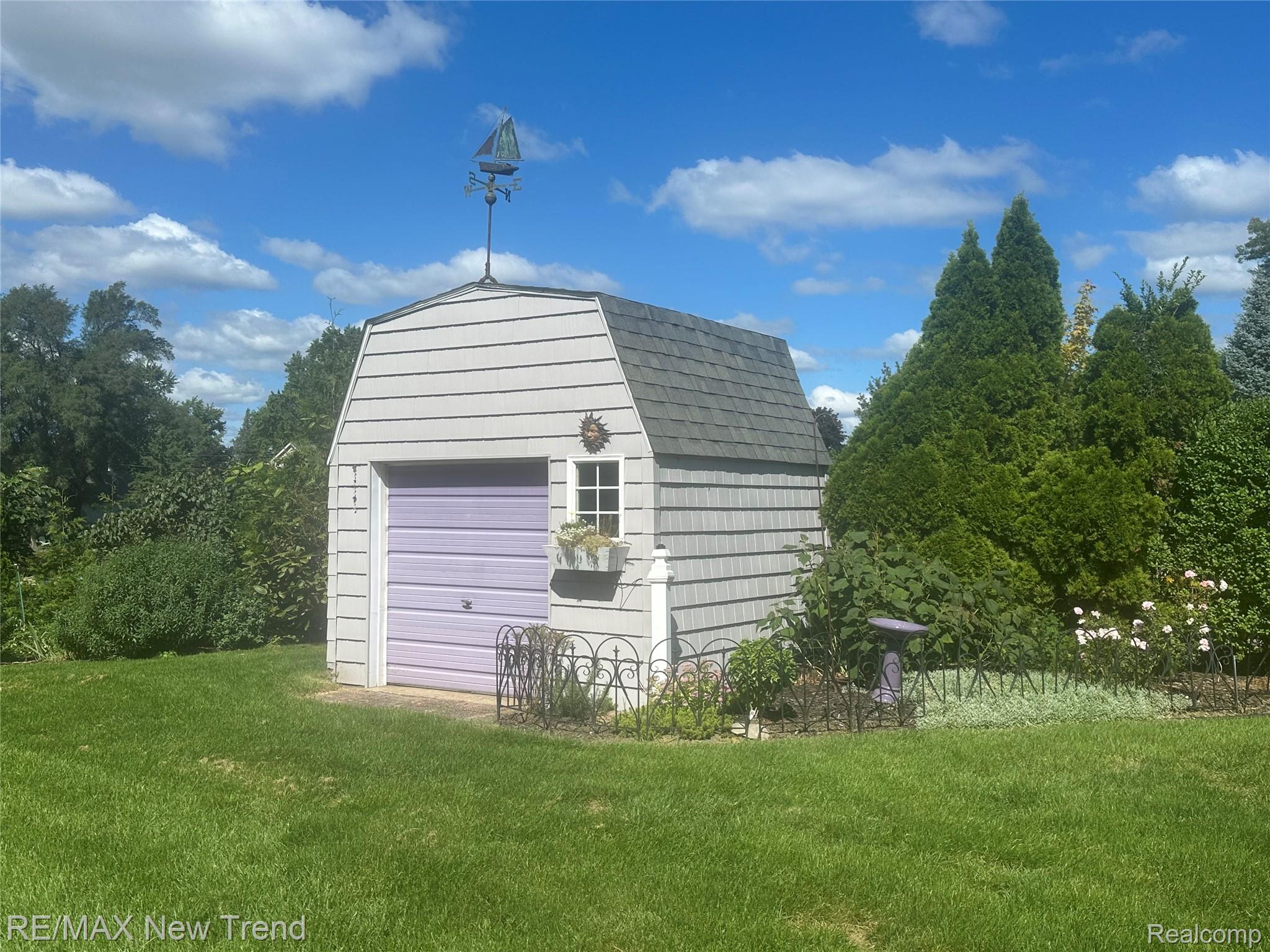 2529 South Commerce Road Walled Lake, MI 48390 - Photo 53 of 66 Gable-roof storage shed with light-colored siding and a lavender roll-up door