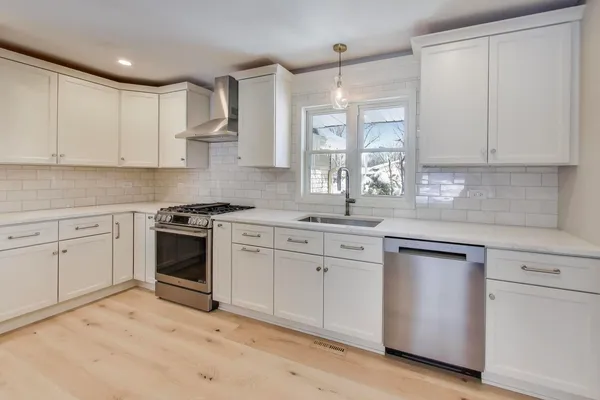 a kitchen with stainless steel appliances white cabinets and wooden floor