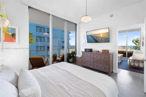 a bedroom with a large bed and a flat tv screen on dresser