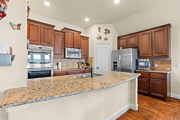 a kitchen with stainless steel appliances granite countertop a sink refrigerator and cabinets