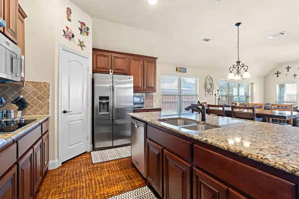 a kitchen with granite countertop kitchen island stainless steel appliances a sink a counter top space and cabinets