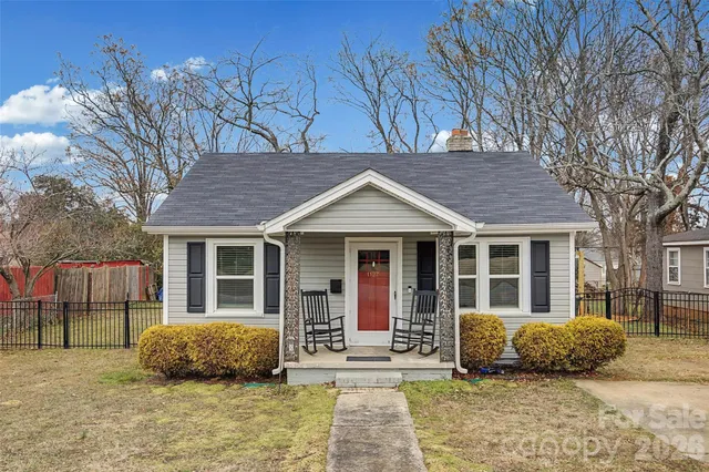 a view of a brick house with large windows and large tree