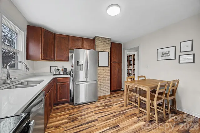 a kitchen with stainless steel appliances kitchen island granite countertop a sink refrigerator and cabinets