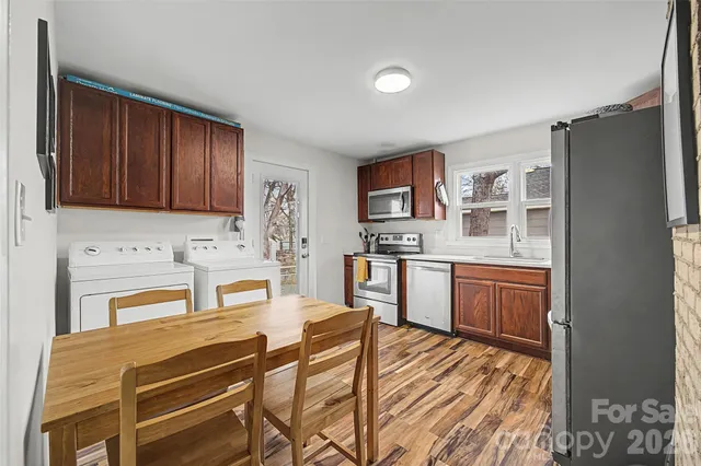 a kitchen with stainless steel appliances a stove a sink cabinets and a wooden floor
