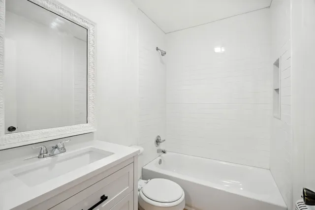 a bathroom with a bathtub shower sink vanity mirror and toilet