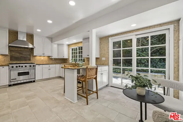 a kitchen with granite countertop a stove a sink and a dining table with chairs