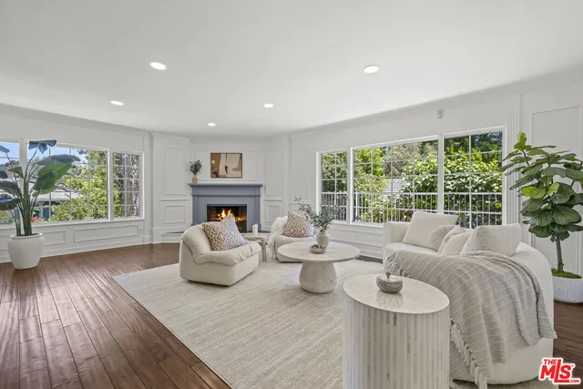 a living room with furniture large window and wooden floor