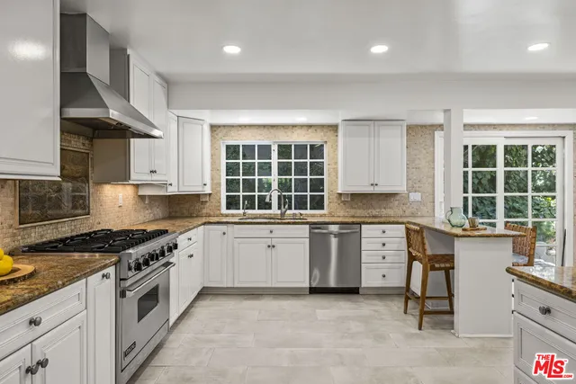 a kitchen with granite countertop a stove a sink and a refrigerator