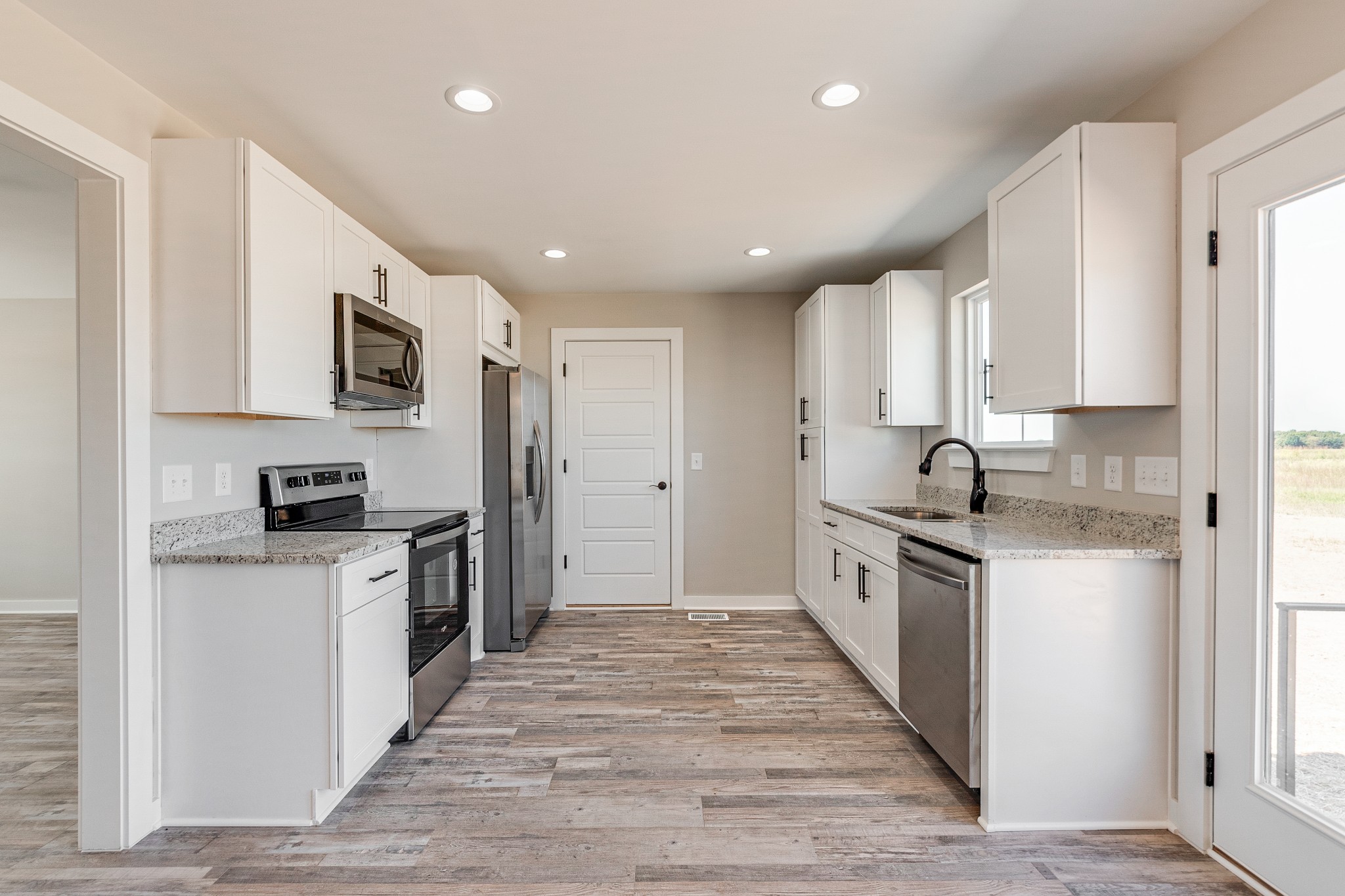 483 Meadows Road Portland, TN 37148 - Photo 15 of 29 a large kitchen with stainless steel appliances granite countertop a stove a sink a refrigerator and white cabinets with wooden floor