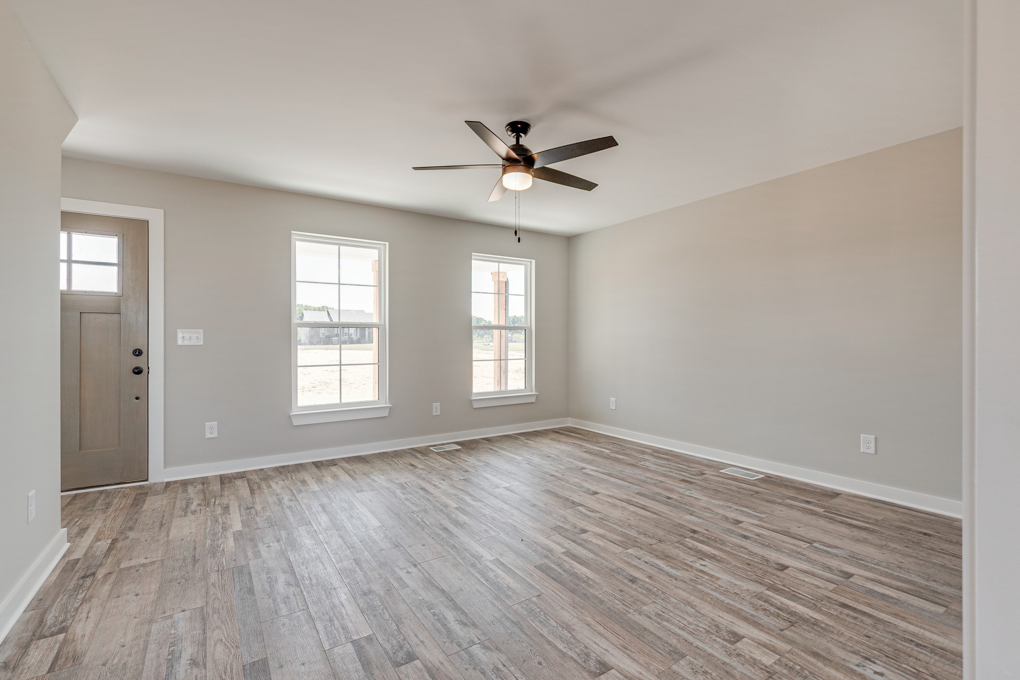 483 Meadows Road Portland, TN 37148 - Photo 7 of 29 an empty room with wooden floor ceiling fan and windows
