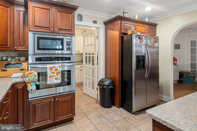 a kitchen with stainless steel appliances granite countertop a refrigerator a stove and a sink with wooden floor