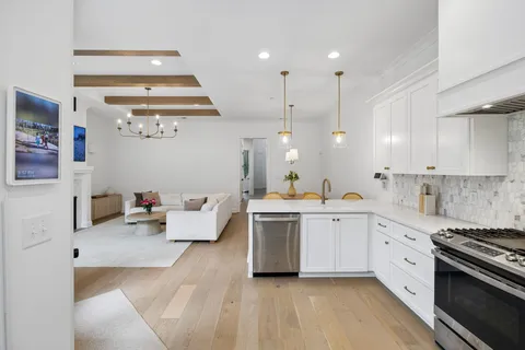 a large white kitchen with a stove a sink dishwasher and a fireplace with wooden floor
