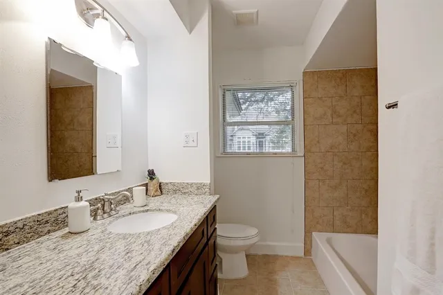 a bathroom with a granite countertop sink a mirror and a toilet