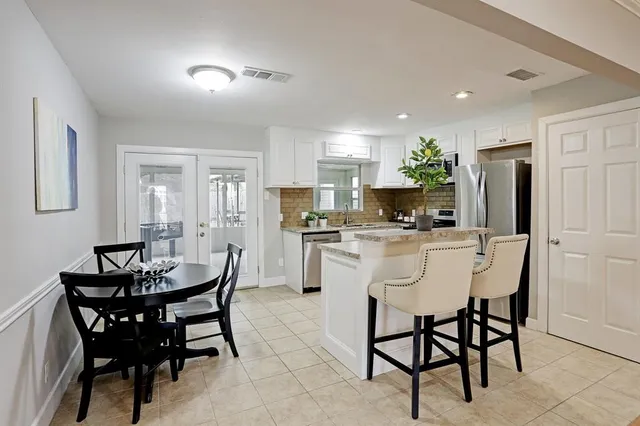 a kitchen with a dining table chairs and refrigerator