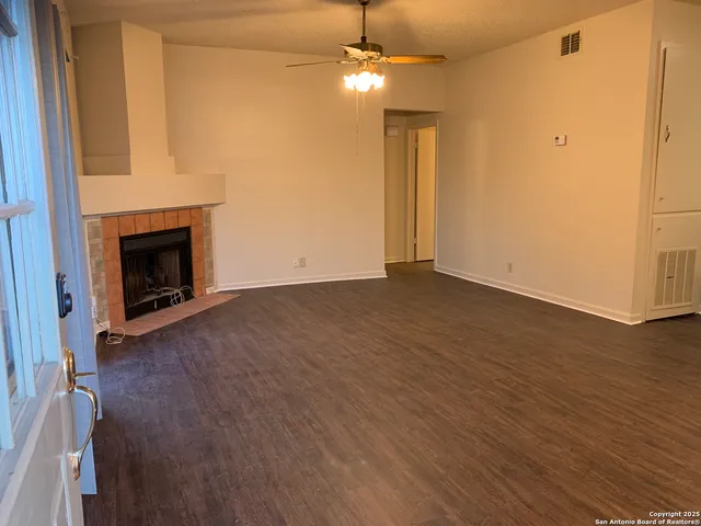 an empty room with wooden floor fireplace and windows