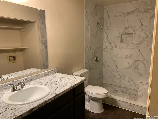 a bathroom with a granite countertop sink toilet a mirror and shower