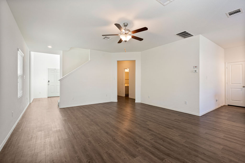 156 Red Buckeye Loop Liberty Hill, TX 78642 - Photo 5 of 27 a view of an empty room with wooden floor and a ceiling fan