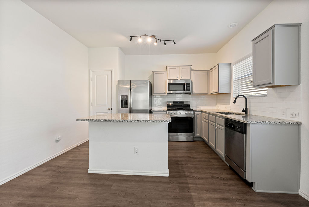 156 Red Buckeye Loop Liberty Hill, TX 78642 - Photo 6 of 27 a kitchen with kitchen island granite countertop a sink cabinets and stainless steel appliances