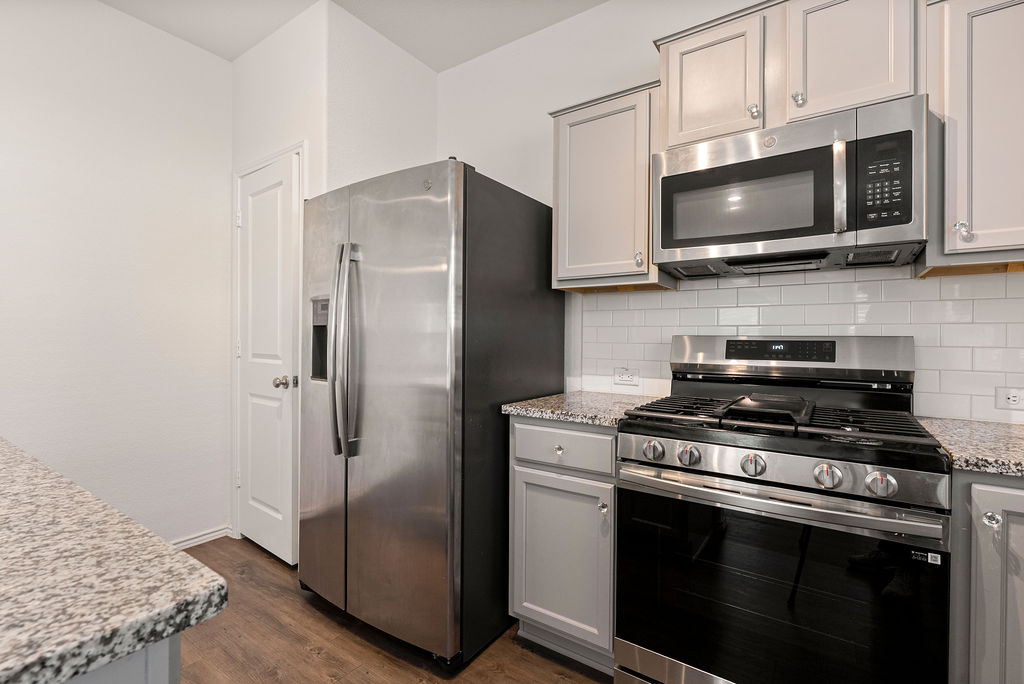 156 Red Buckeye Loop Liberty Hill, TX 78642 - Photo 7 of 27 a kitchen with stainless steel appliances a stove a microwave and a counter space