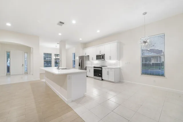 a large white kitchen with stainless steel appliances granite countertop a large counter top and a stove top oven