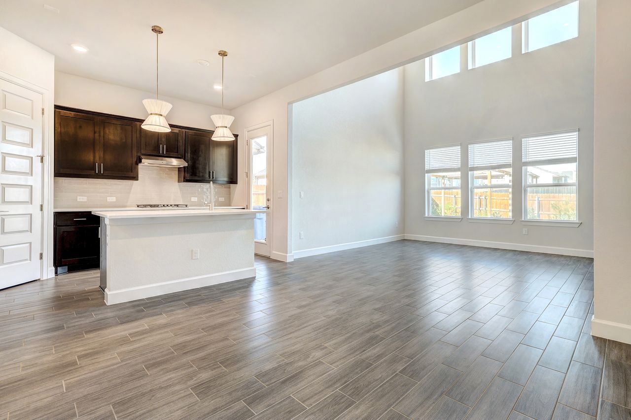 4705 Sea Salt Drive Austin, TX 78747 - Photo 40 of 40 Kitchen featuring a center island with sink, pendant lighting, dark brown cabinets, open floor plan, and wood tiled floors