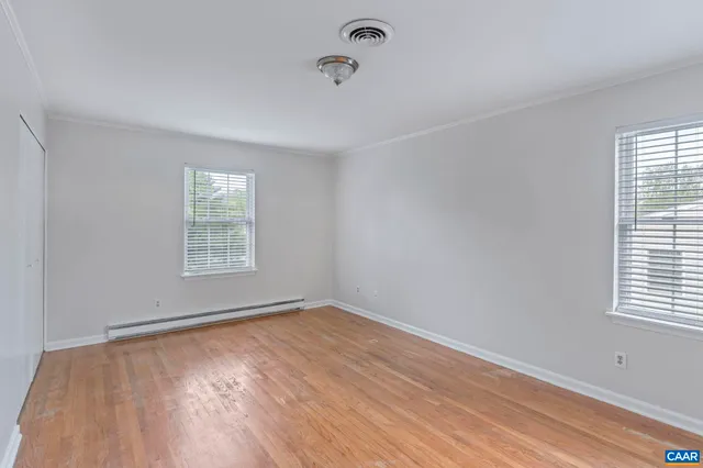 an empty room with wooden floor and windows