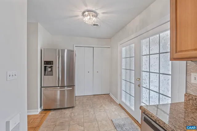 a view of a refrigerator in kitchen and an empty room