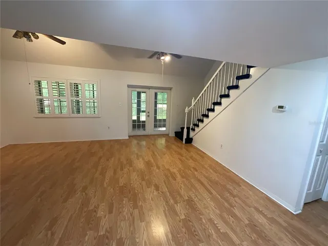 a view of an empty room with wooden floor and stairs