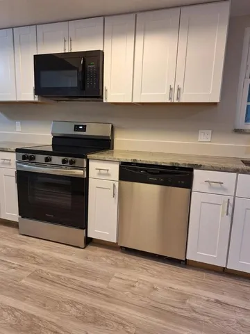 a kitchen with white cabinets stainless steel appliances and wooden floor