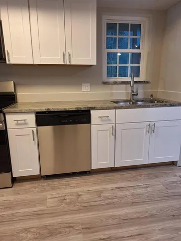 a kitchen with granite countertop wooden cabinets appliances and a sink