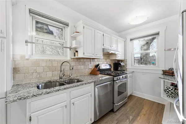 a kitchen with granite countertop a sink cabinets stainless steel appliances and a window