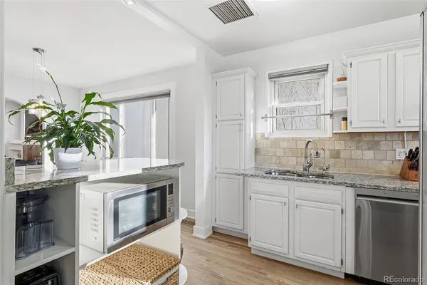 a kitchen with granite countertop a stove a sink and a microwave