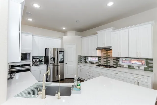 a kitchen with stainless steel appliances kitchen island granite countertop a sink stove and refrigerator