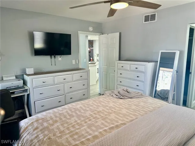 a bedroom with a bed and a flat tv screen on dresser