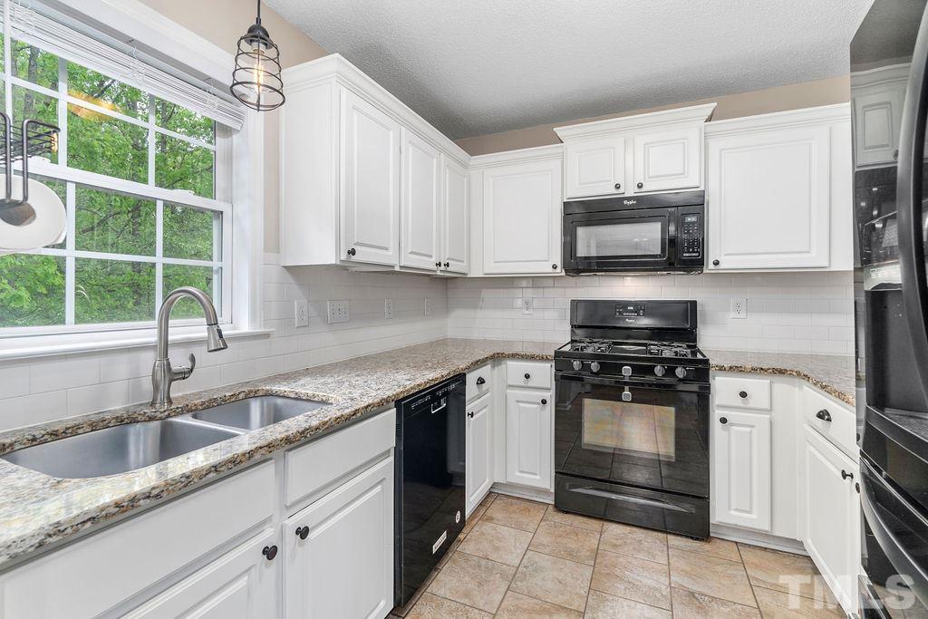 507 Firefly Road Holly Springs, NC 27540 - Photo 11 of 30 Timeless White Cabinetry with Granite Counter Tops, Subway Tile, and Matching Black Appliances with new refrigerator installed in 2019 and new dishwasher in 2017.