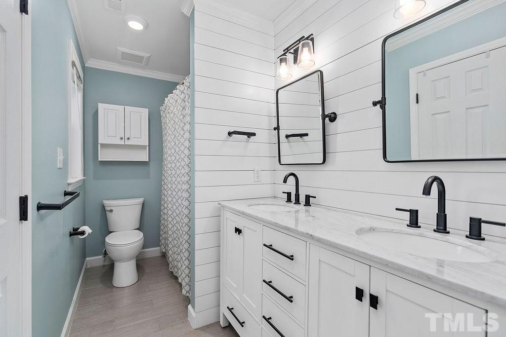 507 Firefly Road Holly Springs, NC 27540 - Photo 15 of 30 Added crown molding, tile floors, dual vanity sink, mirrors and light fixtures, ship lap wall, new toilet, cabinet above the toilet, new hardware.