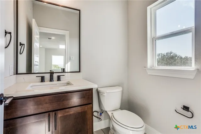 a bathroom with a granite countertop toilet sink and mirror