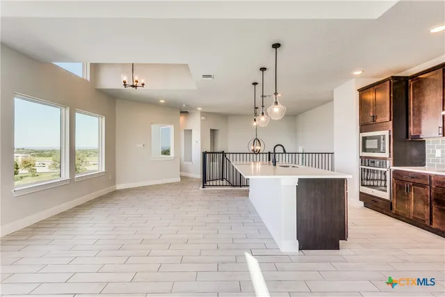 a living room with stainless steel appliances kitchen island granite countertop a sink cabinets and wooden floor