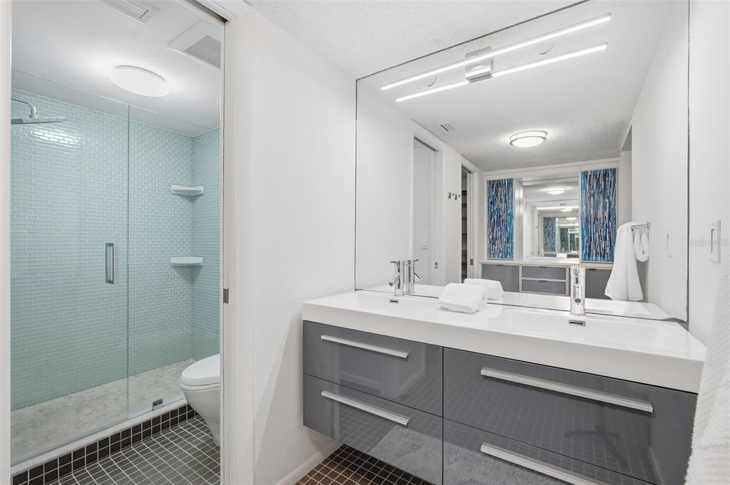 6415 Midnight Pass Road, Unit 211 Sarasota, FL 34242 - Photo 26 of 58 a bathroom with a double vanity sink toilet and shower