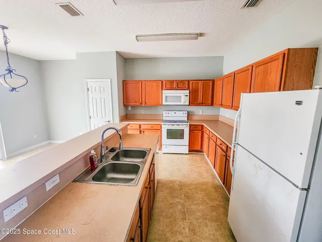 a kitchen with a refrigerator a stove top oven a sink and a large window